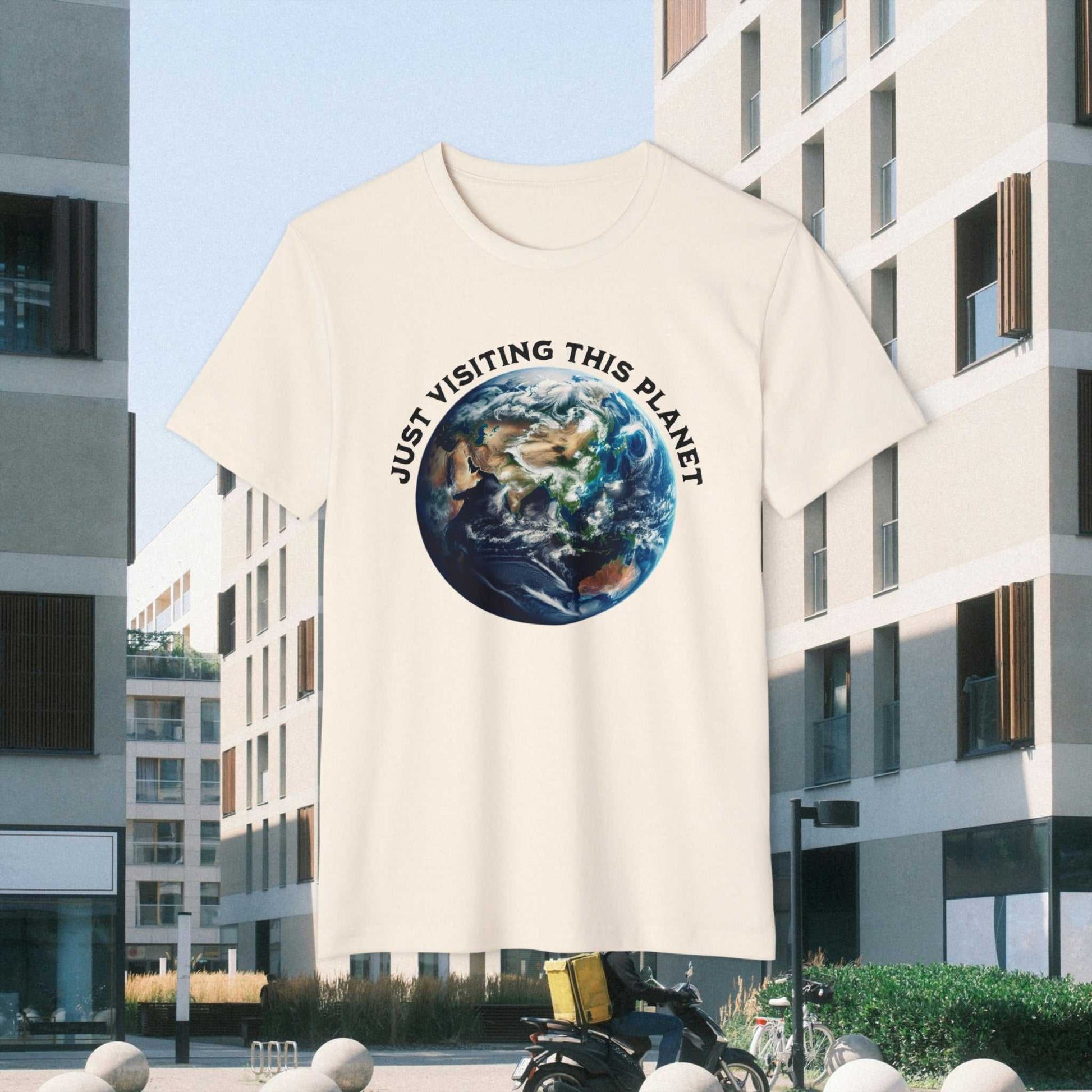 Just Visiting This Planet text w Earth graphic on a natural Tee