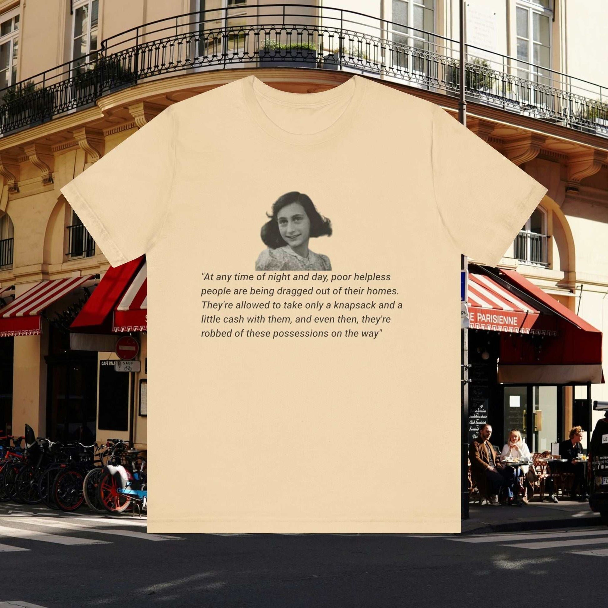 Anne Frank quote on soft cream tee: At any time of night and day, poor helpless people are being dragged out of their homes. They're allowed to take only a knapsack and a little cash with them, and even then, they're robbed of these possessions on the way.Anne Frank Abductions Quote on Tan tee