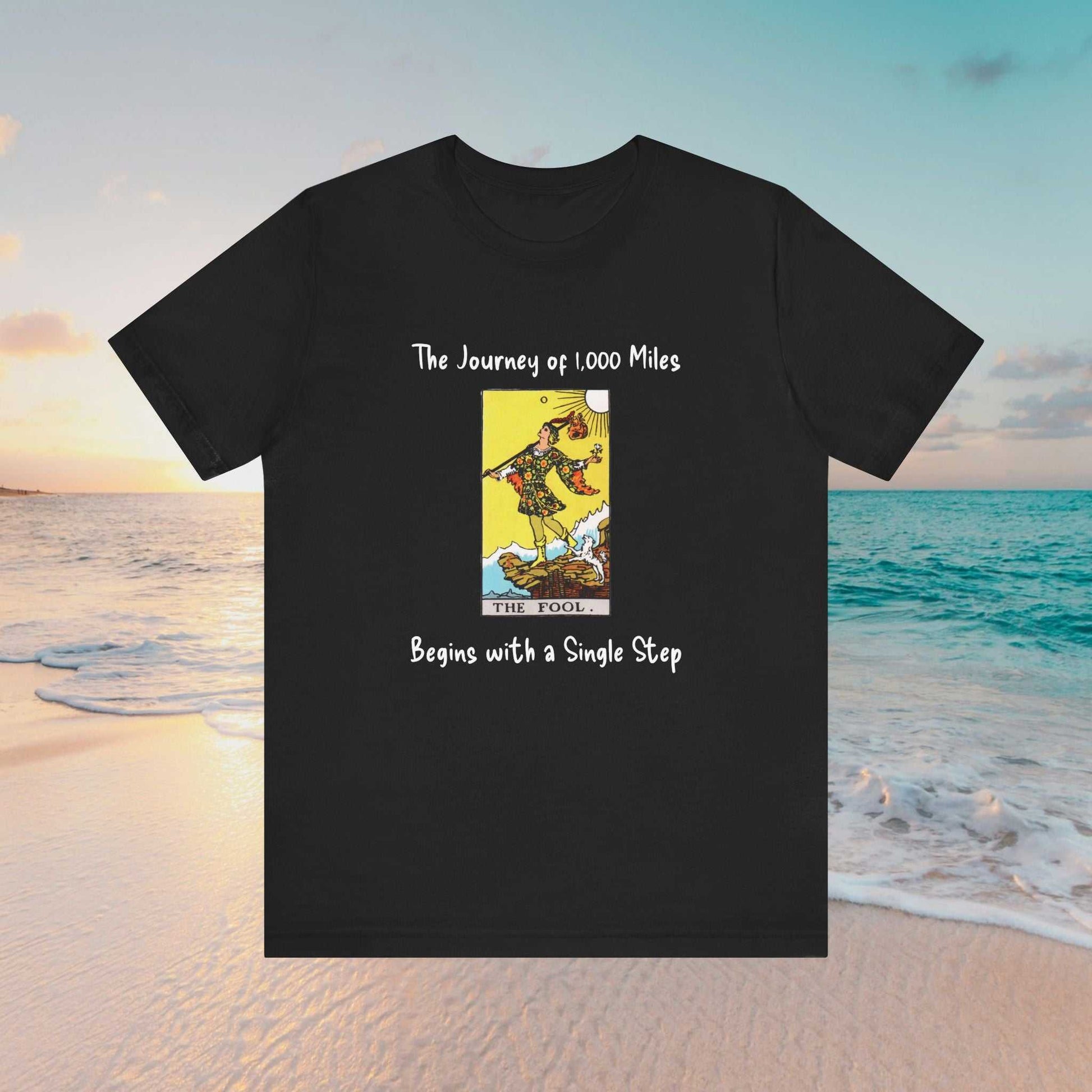 The Fool tarot graphic and text of 'The Journey of 1,000 Miles Begins with a Single Step" on a black tee