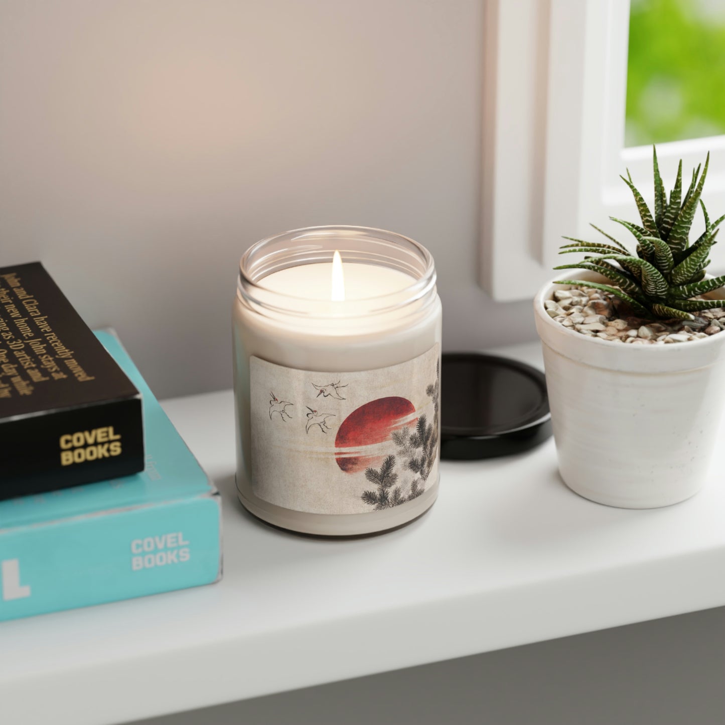 "Clean Cotton" Scented Soy Candle jar with Hokusai print 'birds and sunset' on white table by aloe plant and book