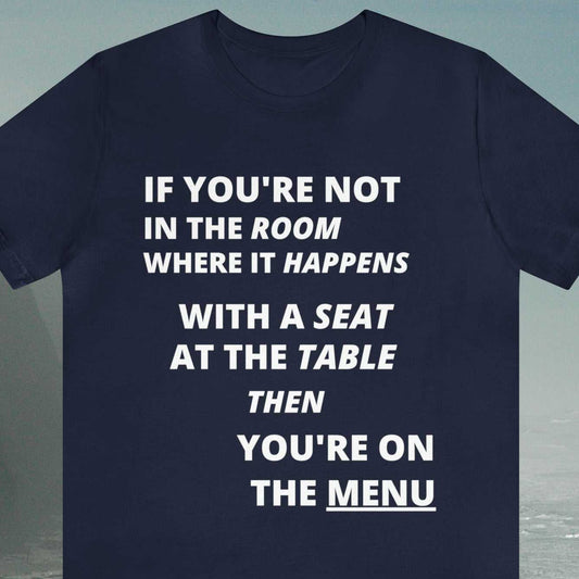 Activist. 'If you're not in the room where it happens with a seat at the table, then you're on the menu' text ona navy tee.